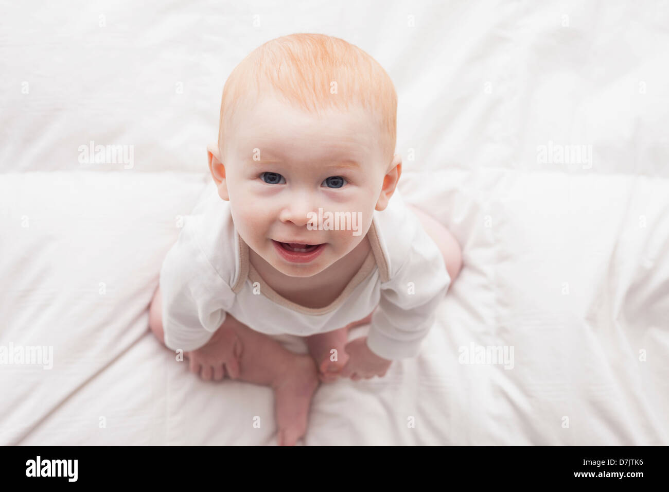Direttamente sopra il ritratto di baby boy (18-23 mesi) seduto sul piumone e guardando la fotocamera Foto Stock