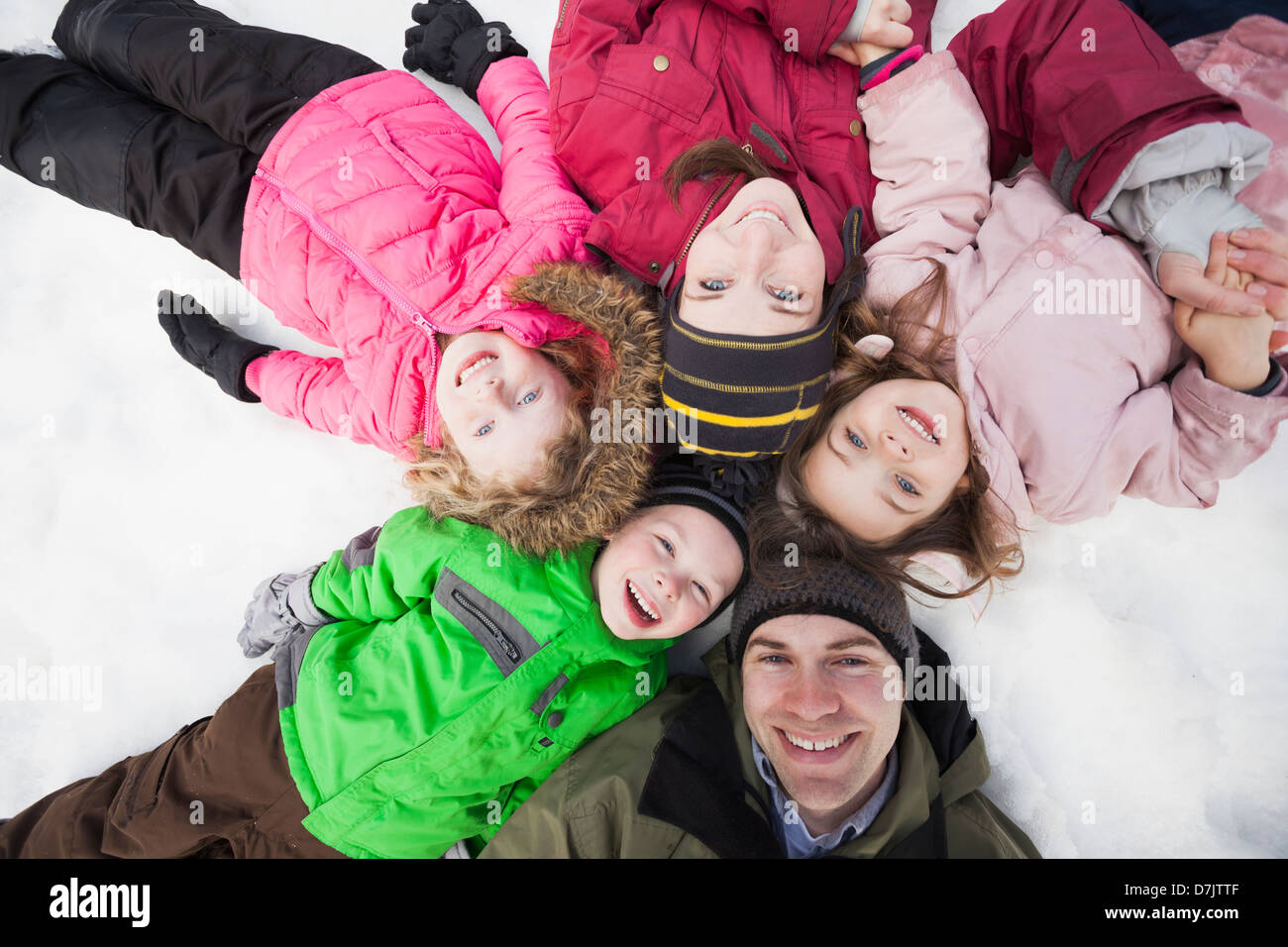 Direttamente sopra il ritratto di tre bambini (2-3, 4-5) con i genitori che giace sulla neve Foto Stock