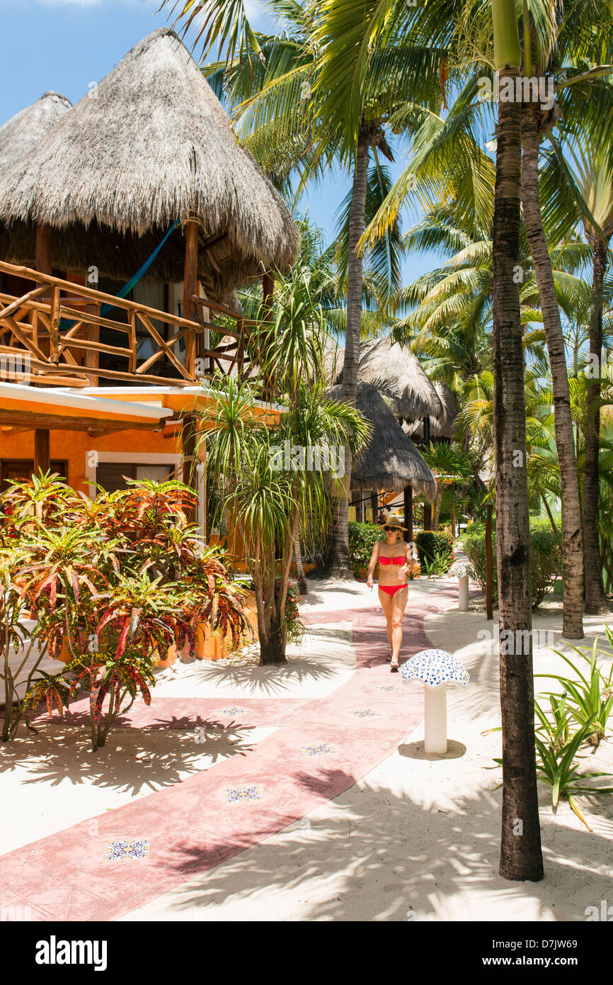 Mahekal Beach Resort,stile cabana alloggio sulla spiaggia con una donna che cammina lungo il percorso Foto Stock