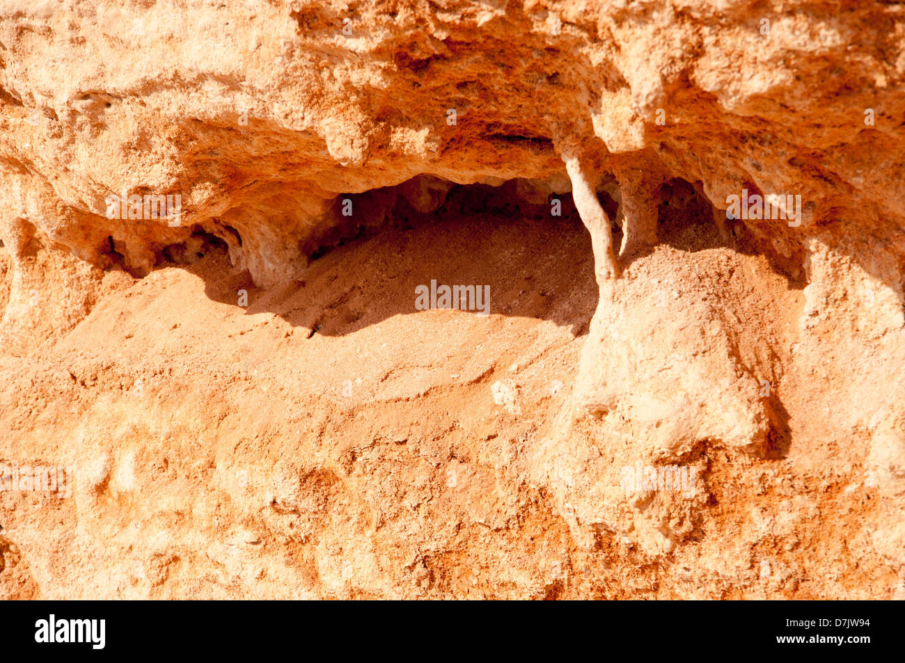 Piccola Grotta Stalattitica e-come feature su un soffice roccia rossa. Foto Stock