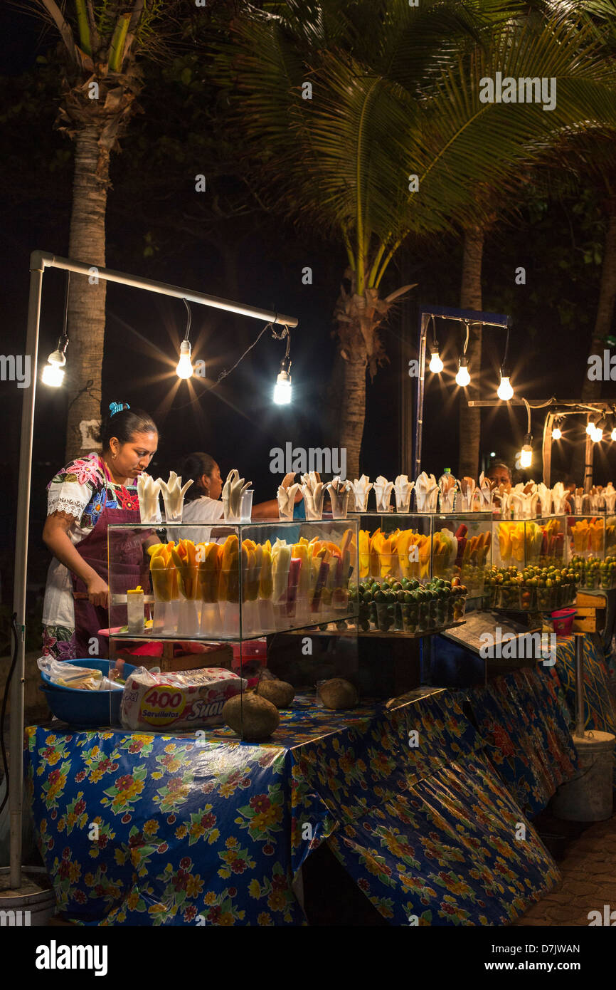 Donna maya vendono frutta sbucciata a un cavalletto di cibo la sera Foto Stock
