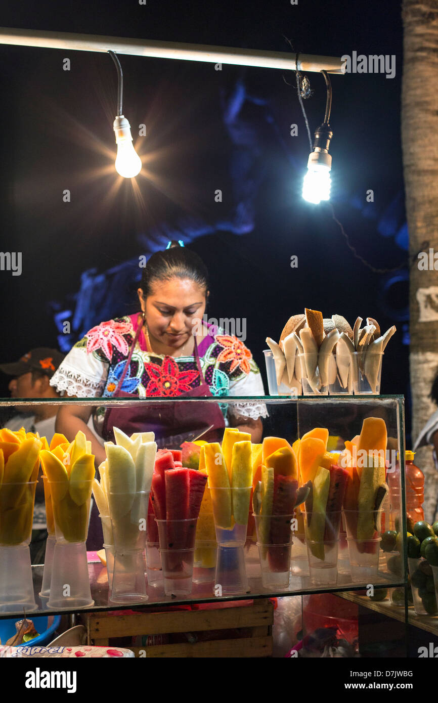 Donna maya vendono frutta sbucciata a un cavalletto di cibo la sera Foto Stock