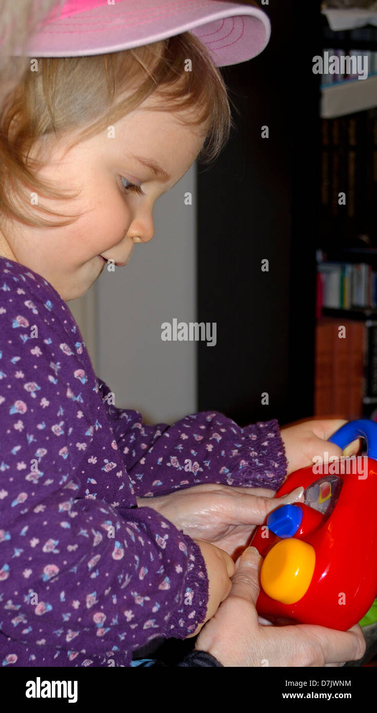 2 anni di bambina di giocare con il giocattolo rossa Foto Stock