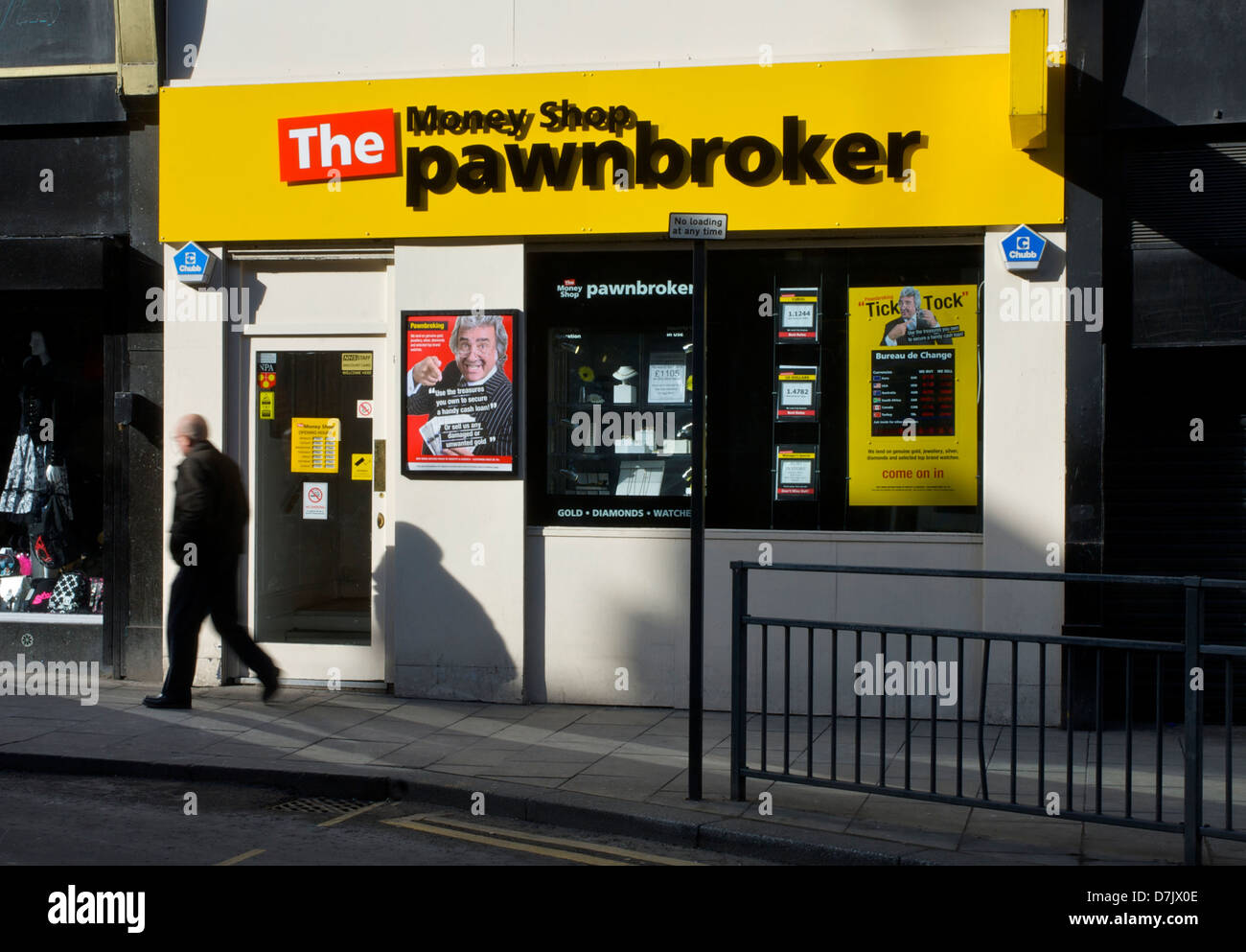 Uomo che cammina passato il denaro Shop pawnbroker, Leeds, West Yorkshire, Inghilterra, Regno Unito Foto Stock