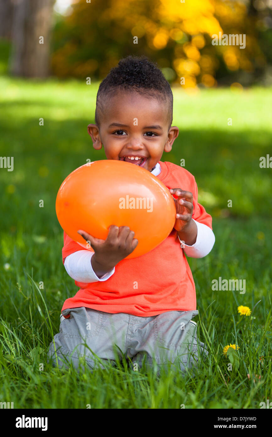 Outdoor ritratto di un simpatico giovane bambino nero gioca con un palloncino - popolo africano Foto Stock
