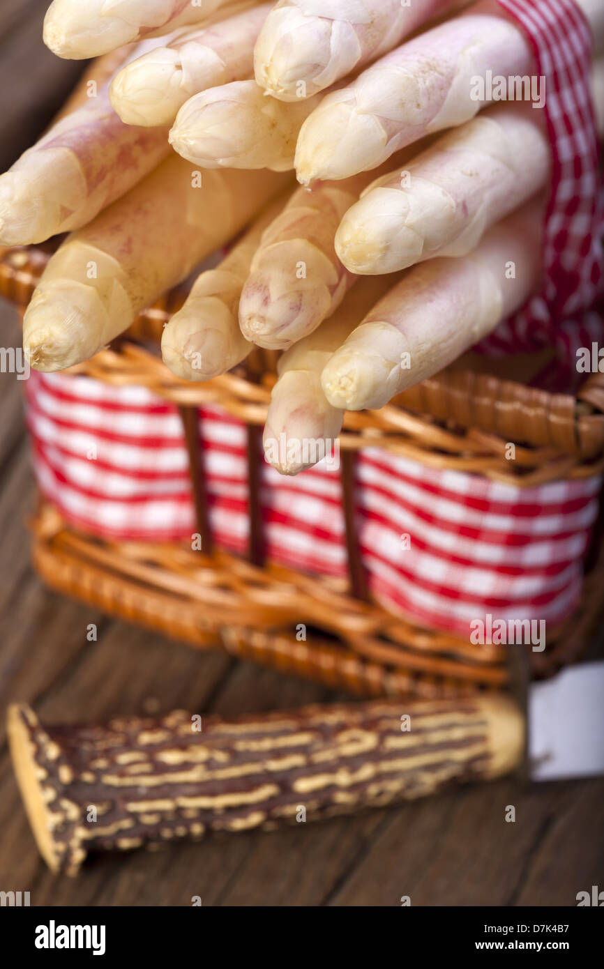 Asparagi bianchi legate con un nastro di tessuto in una cesta e un coltello con impugnatura in corno di bue Foto Stock