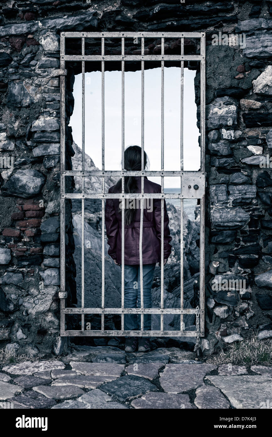 Una ragazza dietro un traliccio porta, guardando verso il mare Foto Stock