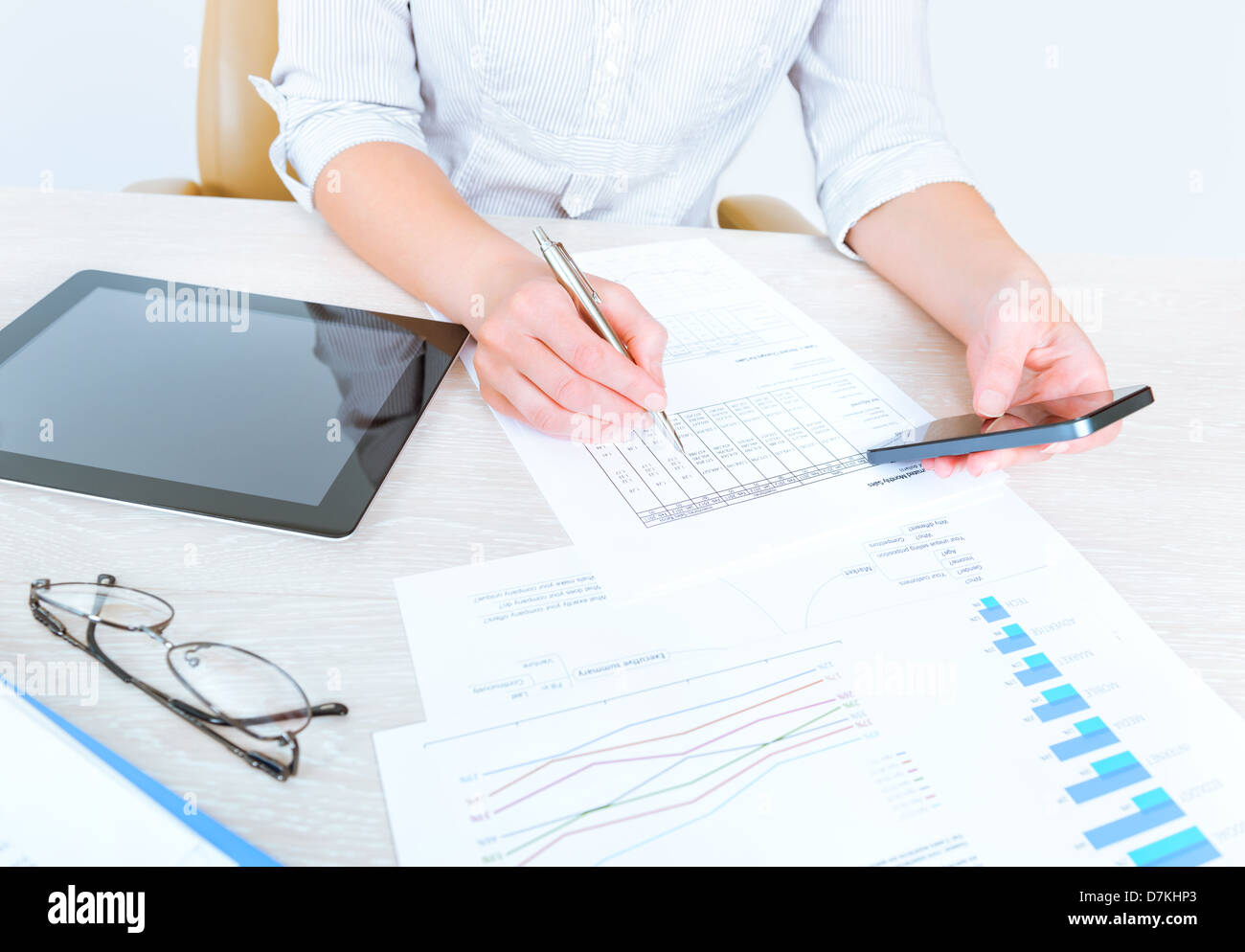 Imprenditrice di successo seduto alla scrivania in un abbigliamento informale e utilizzando i moderni dispositivi per analizzare le statistiche di vendita Foto Stock