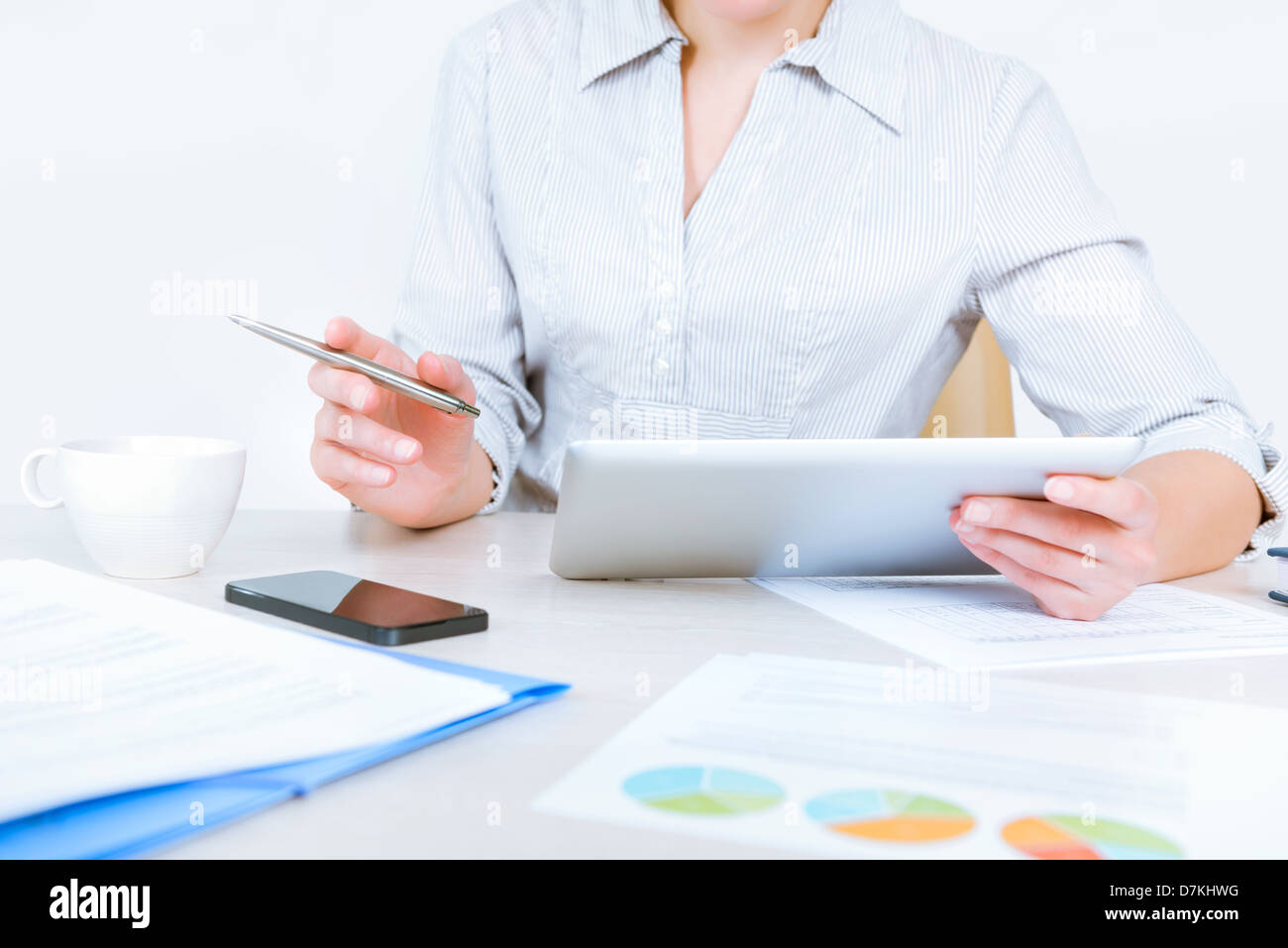 Imprenditrice rilassata indossando Camicia casual seduto alla scrivania e lavorare con i dati sulla tavoletta digitale in ufficio Foto Stock