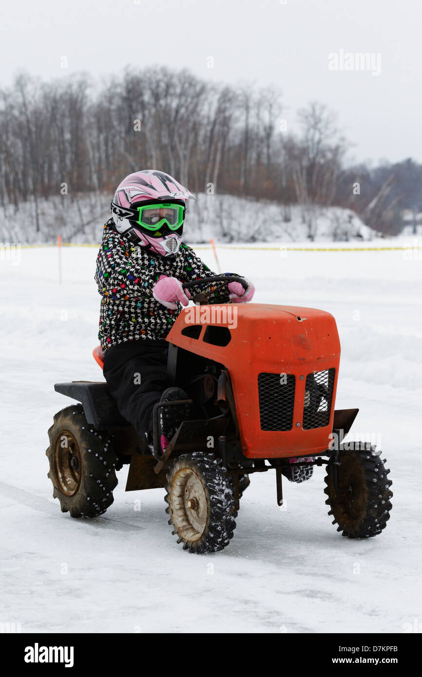 Un giovane pilota un vecchio tosaerba durante un pre-event parade prima che la prima relazione annuale di tosaerba gare di ghiaccio sul lago di coltello. Foto Stock