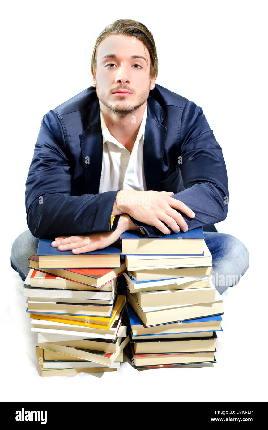 Bello studente di college stanchi sulle pile di libri, isolato su bianco Foto Stock