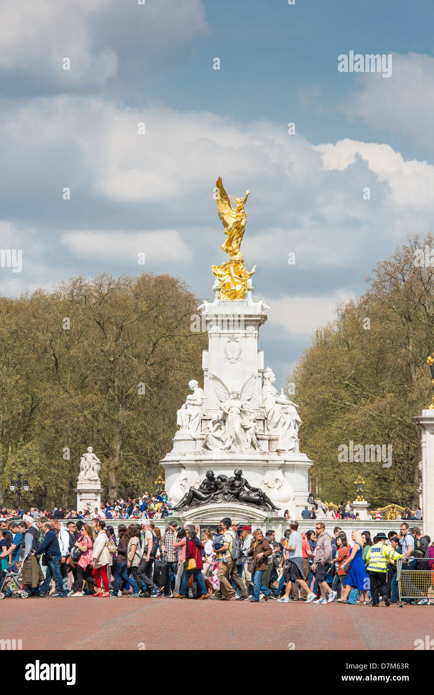 Turisti attraversando la strada di fronte alla regina Victoria monumento accanto a Buckingham Palace di Londra. Foto Stock