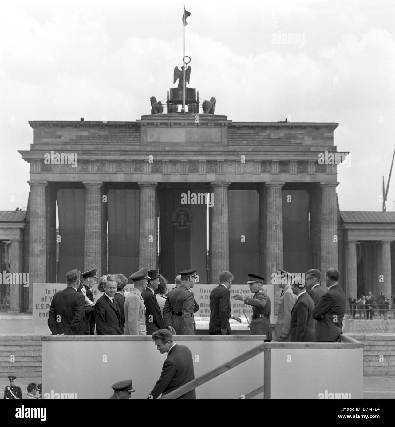 Il presidente statunitense John Fitzgerald Kennedy in corrispondenza di un punto di vista presso il muro di Berlino il 26 giugno 1963. La Porta di Brandeburgo per motivi di easten parte della città divisa è stata coperta con le bandiere rosse. Foto Stock