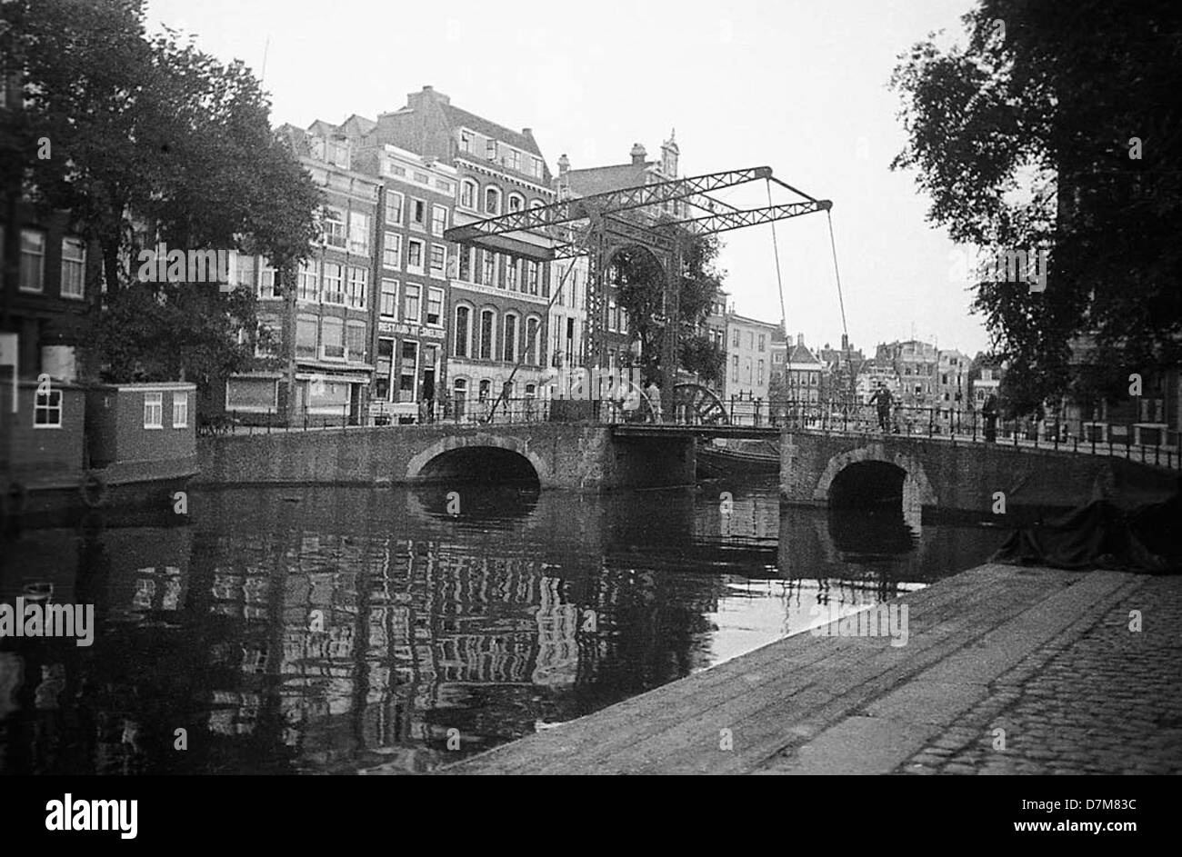 Questa fotografia mostra un ponte che attraversa il canale Kloveniersburgwal ad Amsterdam, nei Paesi Bassi. L'immagine evidenzia l'architettura classica del ponte e il suo ruolo nell'intricato sistema di canali della città. Foto Stock