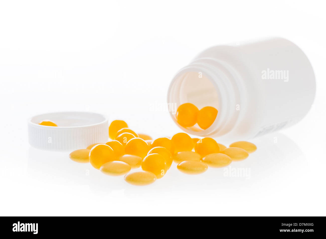 Giallo pillole sparse nella parte anteriore della parte in plastica bianca jar. Foto Stock