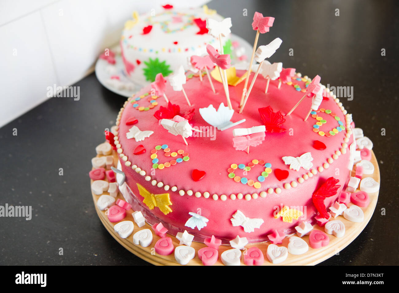 Decorazioni colorate di bianco e rosa marzapane torte per una festa di compleanno sul comò da cucina Foto Stock