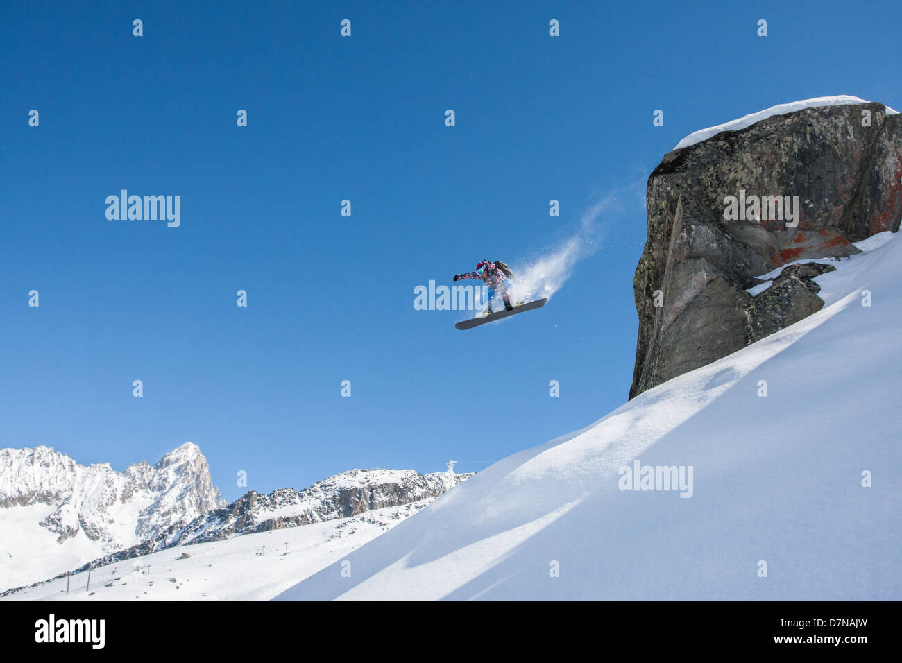 Snowboarder jumping una grande roccia con un famoso Chamonix stile di sfondo. Foto Stock