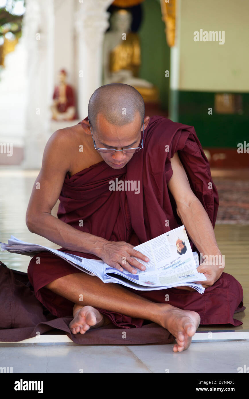 Monaco leggendo un giornale alla Shwedagon pagoda in Yangon, Myanmar Foto Stock