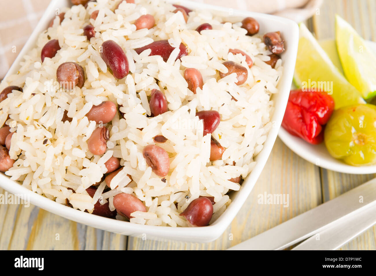 Riso e piselli - Caraibi il cocco riso con fagioli rossi, cowpeas e piselli di piccione. Scotch Bonnet peperoncini e lime sul lato. Foto Stock