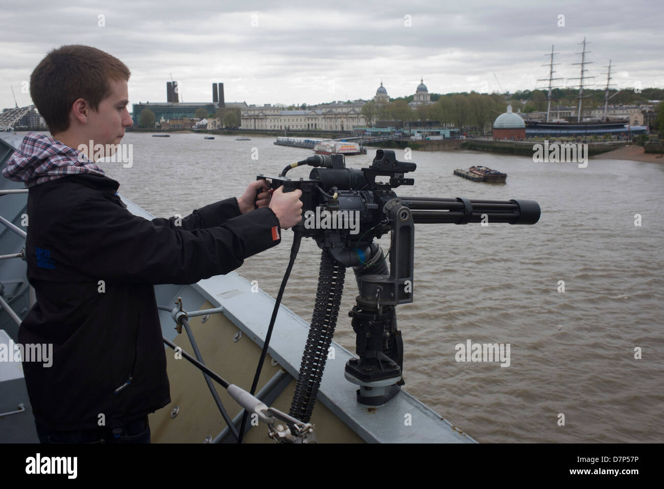 A quindici anni punti adolescente un cannone Minigun dal pianale superiore di HMS illustre sul fiume Tamigi a Greenwich, Londra. Durante il quale la Royal Navy la portaerei era inserito sul fiume permettendo al contribuente al pubblico il suo tour ponti prima della sua decommisioning. Il personale della Marina ci ha aiutato con il PR evento oltre il fine settimana di maggio, storicamente la casa di Gran Bretagna flotta navale. Foto Stock