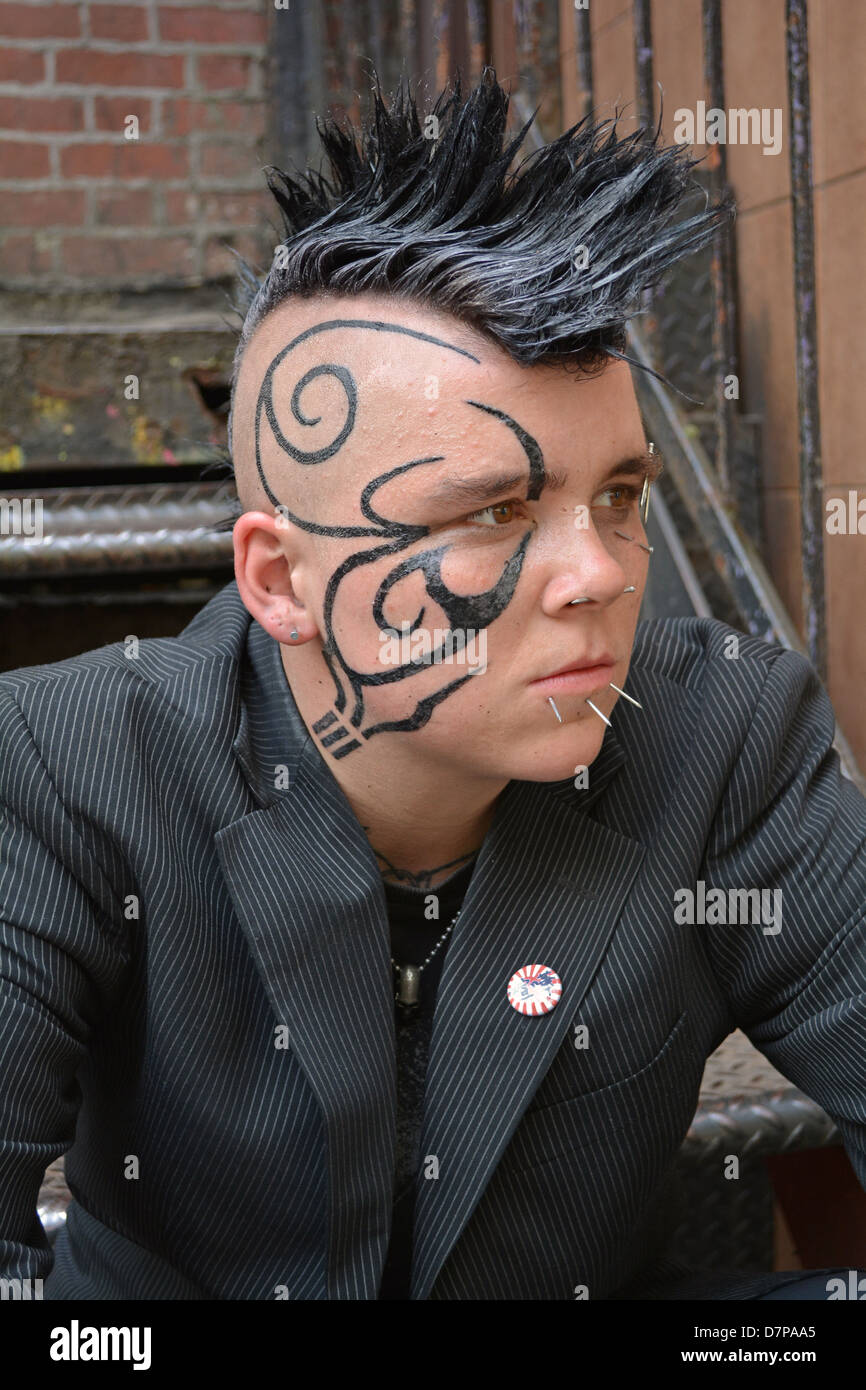 Ritratto di un sesso persona ambigua nel Greenwich Village con un taglio di capelli Mohawk, faccia tatuaggi e piercing multipli Foto Stock