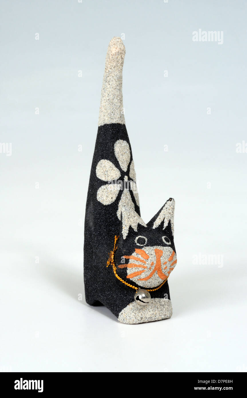 Gatto in pietra con campana attorno al collo ornamento contro uno sfondo bianco. Foto Stock