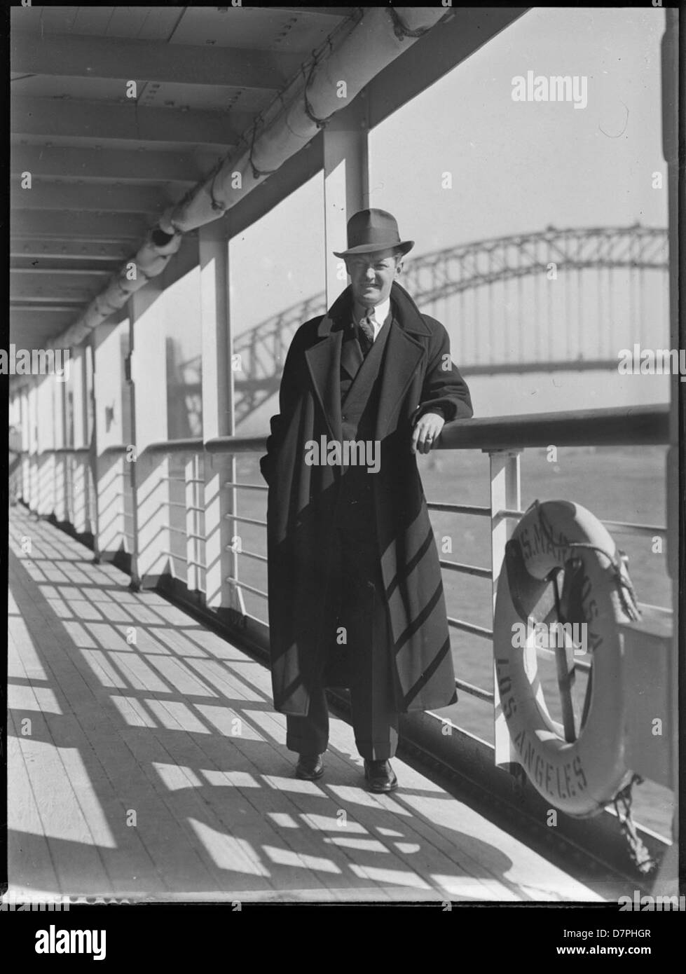Un uomo è mostrato a bordo della SS Mariposa nel porto di Sydney, Australia. La SS Mariposa era gestita dalla Matson Lines ed è raffigurata vicino al Sydney Harbour Bridge. L'immagine mette in evidenza le iconiche navi di Matson e il loro ruolo significativo nel viaggio trans-Pacifico. Foto Stock