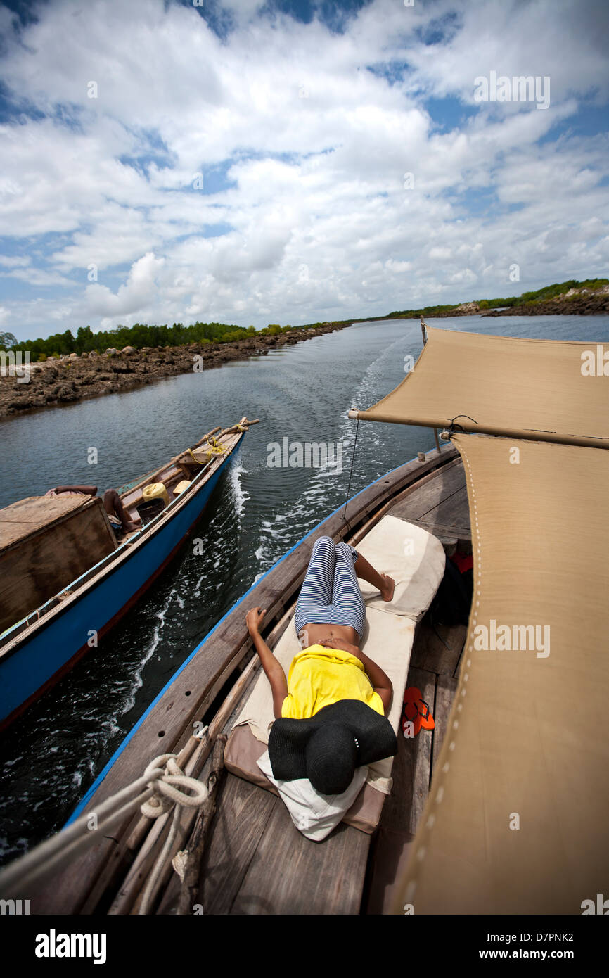 Ragazza recante sul lato di una imbarcazione a vela che viaggiano in una posizione remota Foto Stock