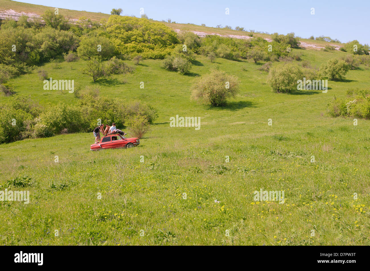 Piccola auto rossa (Zaporozhets) pilotato da un sacco di gente sul campo, Crimea, Ucraina, Europa orientale Foto Stock