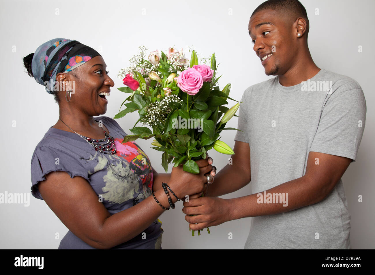 Cresciuto figlio dando la sua mamma fiori Foto Stock
