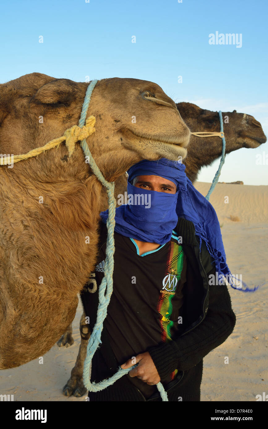 Giovane beduino con dromedari sulle dune a Douz, sud della Tunisia. Foto Stock