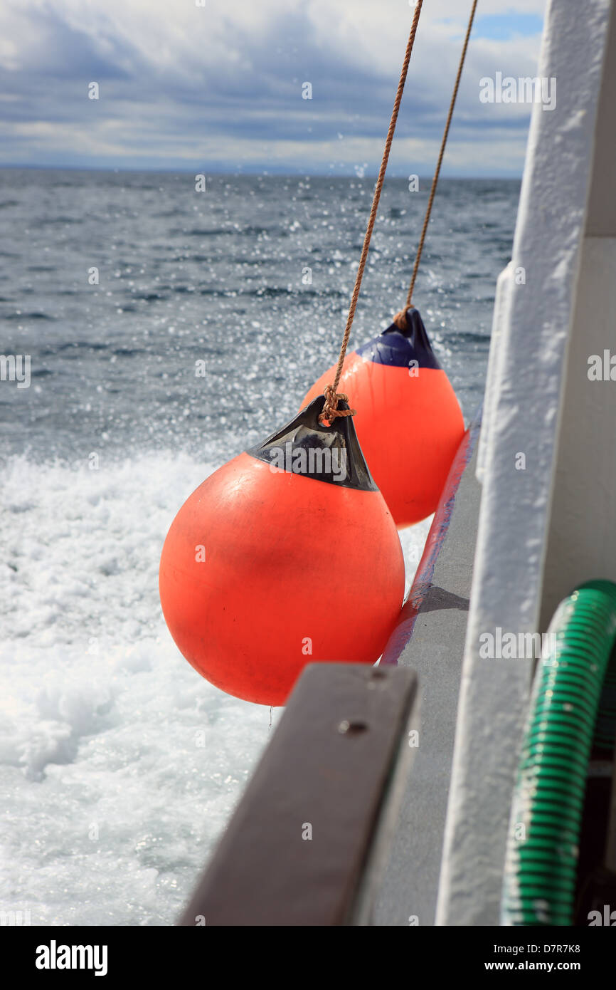 Parafanghi arancione sul lato di una barca mentre fuori in mare Foto Stock
