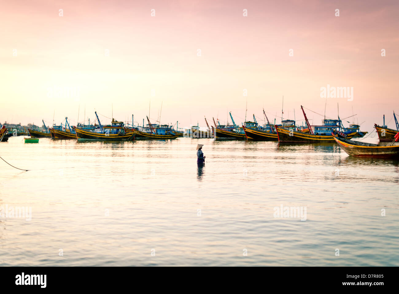 Un pescatore casting net presso la spiaggia di Mui Ne, Vietnam Foto Stock