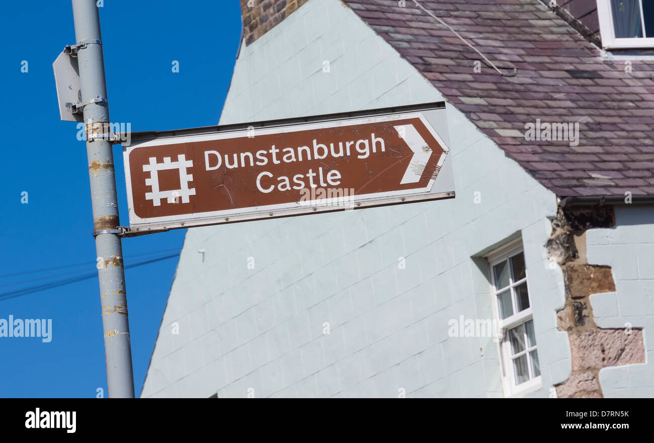 Il castello di Dunstanburgh Signpost presso il piccolo villaggio di pescatori di Craster in Northumberland Foto Stock