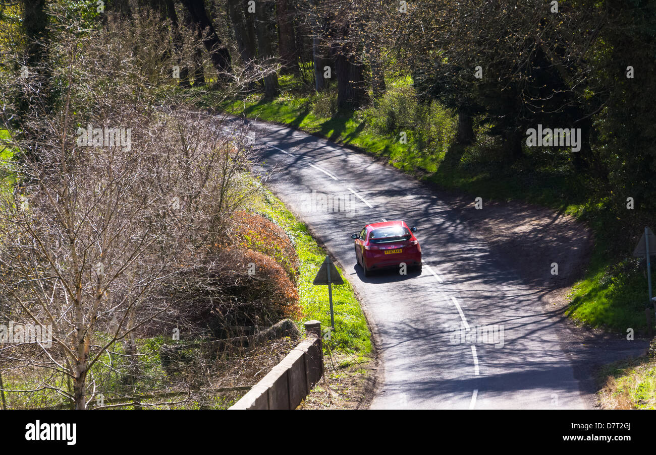 Auto guidando lungo una strada di campagna sotto il sole Foto Stock