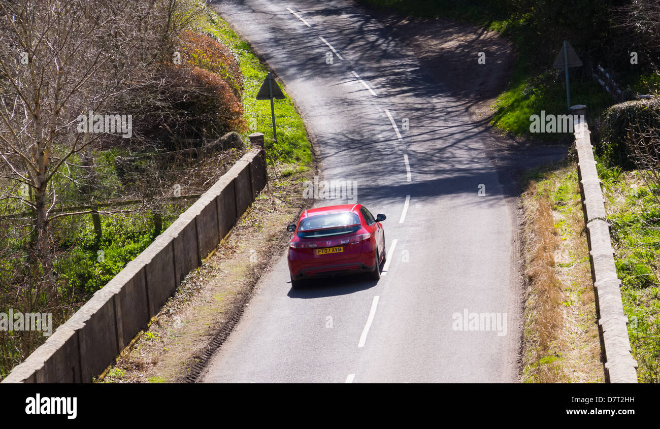 Auto guidando lungo una strada di campagna sotto il sole Foto Stock