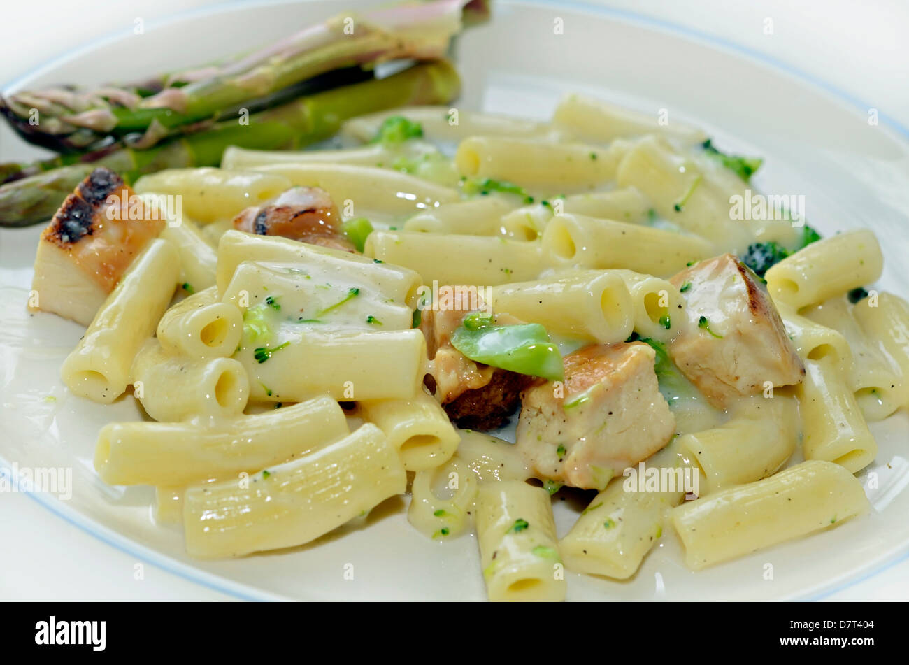 Un pasto di pollo, pasta e broccoli in salsa Alfredo con freschi Asparagi organico su una piastra. Foto Stock