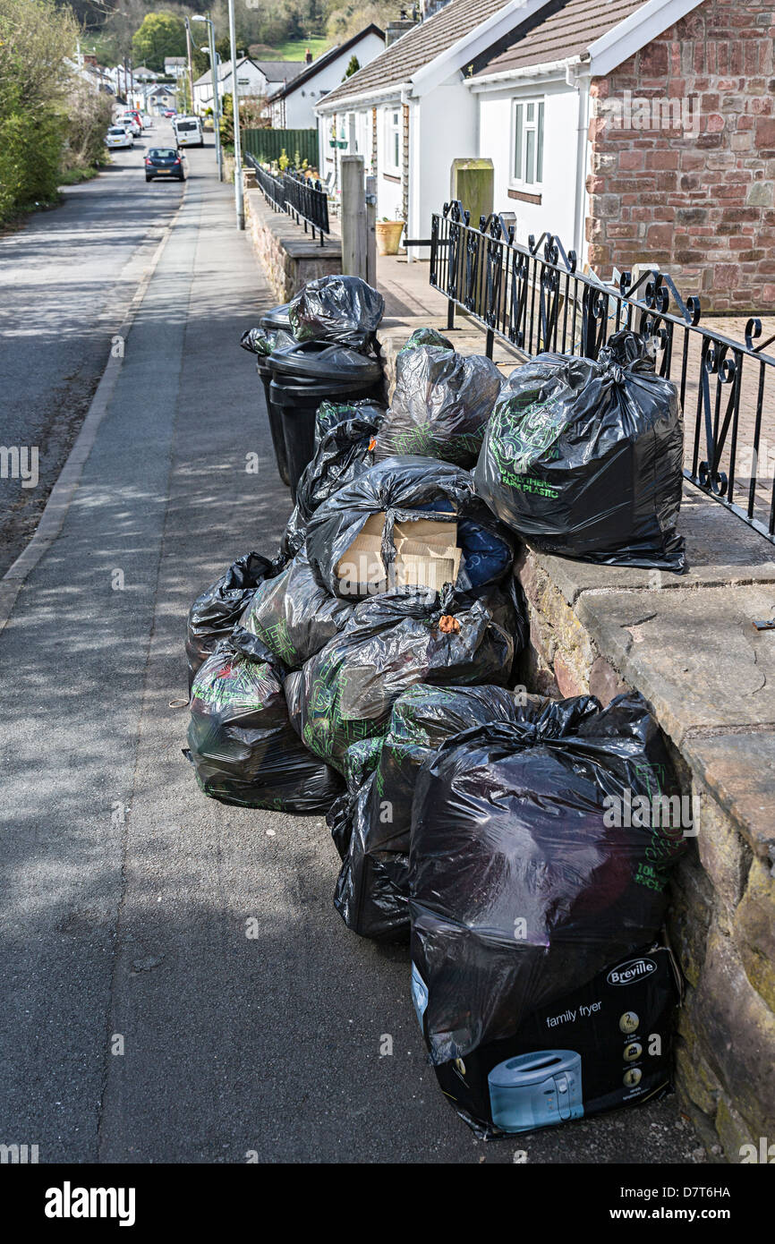 Borsa nera raccolta rifiuti Rifiuti in village street, Wales, Regno Unito Foto Stock