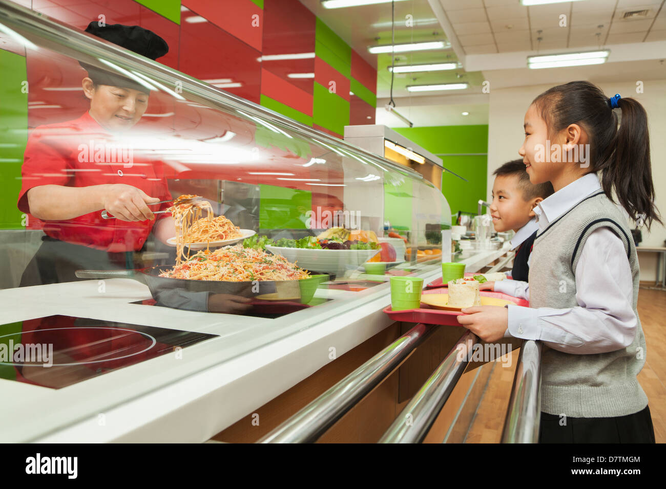 La scuola dei bambini in piedi in linea nella mensa scolastica Foto Stock