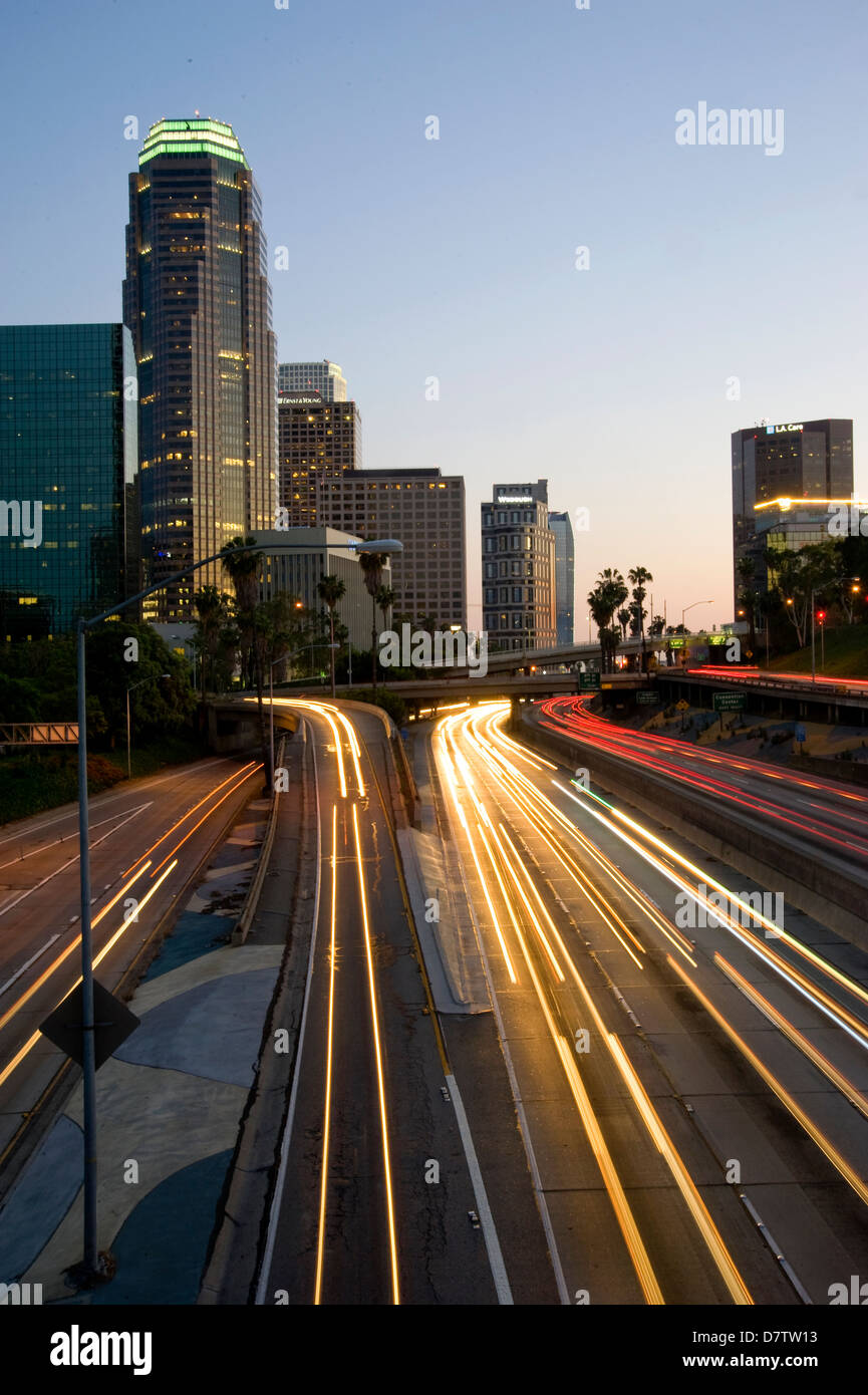 I fari scricchiolano sulla superstrada passando per il centro di Los Angeles al crepuscolo, CA, USA Foto Stock