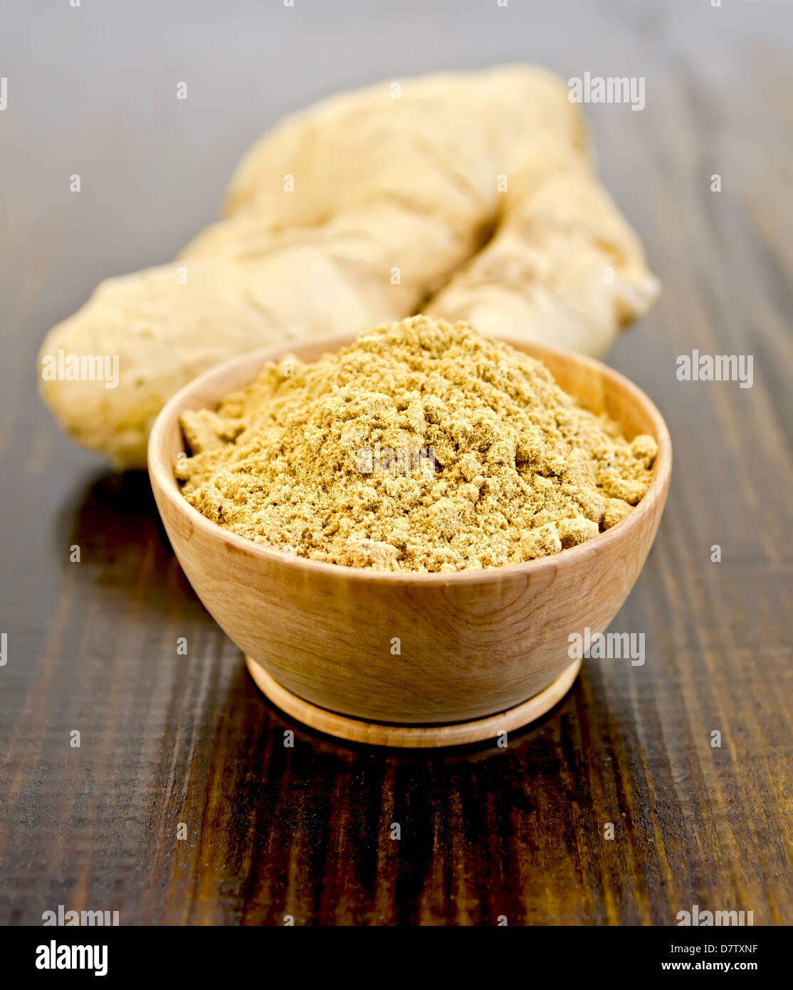 Ciotola di legno con lo zenzero in polvere, radice di zenzero sullo sfondo del pannello di legno Foto Stock
