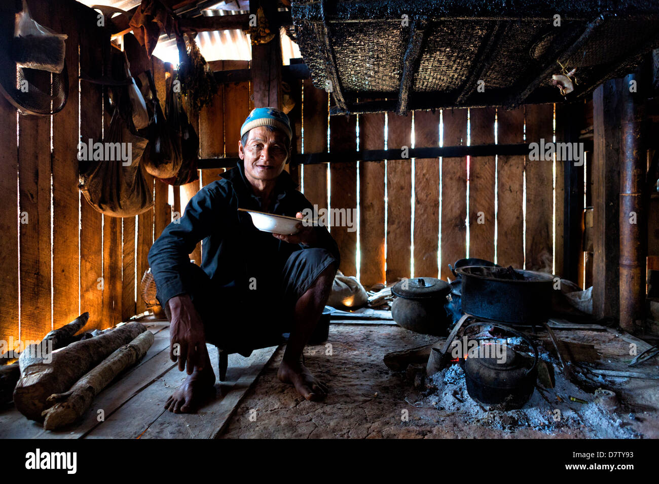 Uomo animista della tribù di Ann mangiare nella sua casa da un fuoco aperto, Panlor Village, vicino a Kengtung (Kyaingtong), Stato Shan, Birmania Foto Stock