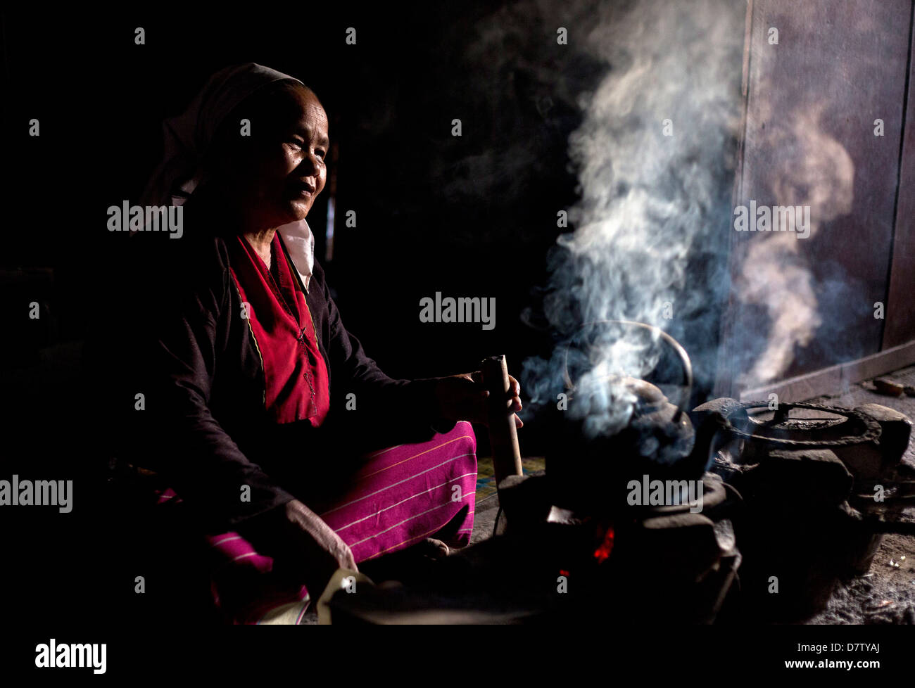 Donna della tribù Palaung per la cottura sul fuoco aperto nella sua casa di villaggio nei pressi di Kengtung (Kyaingtong), Stato Shan, Birmania Foto Stock