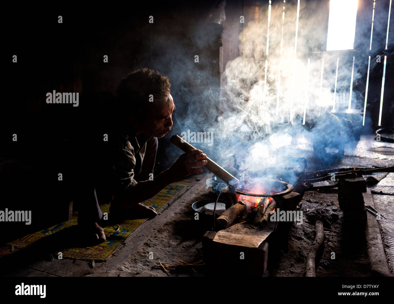 L'uomo della tribù Palaung per la cottura sul fuoco aperto nella sua casa di villaggio nei pressi di Kengtung (Kyaingtong), Stato Shan, Birmania Foto Stock