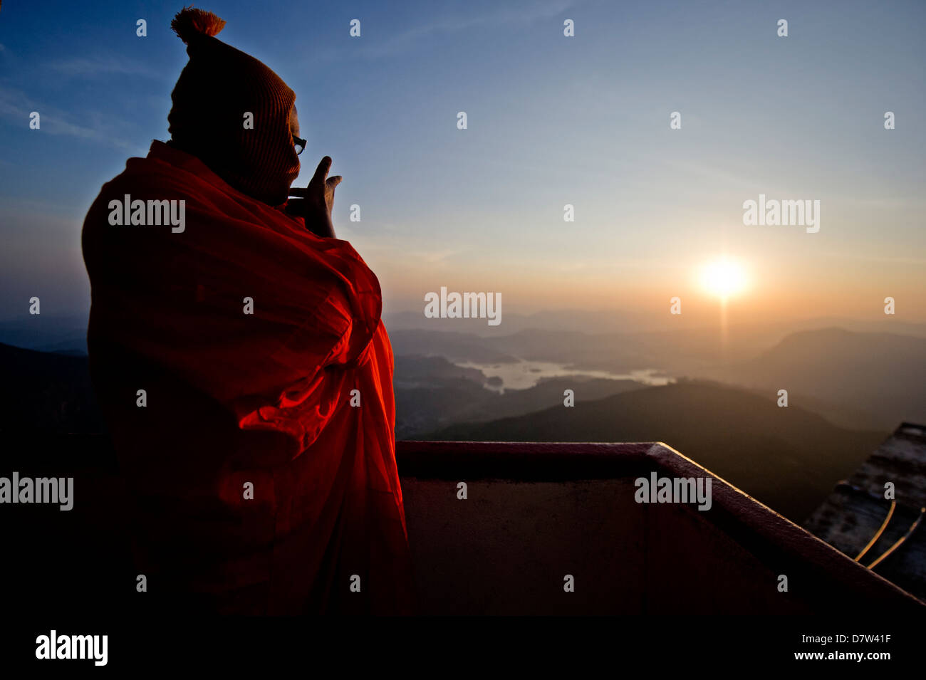Un monaco si affaccia su un tramonto dalla cima della montagna sacra Sri Pada (Adam's Peak), Sri Lanka Foto Stock
