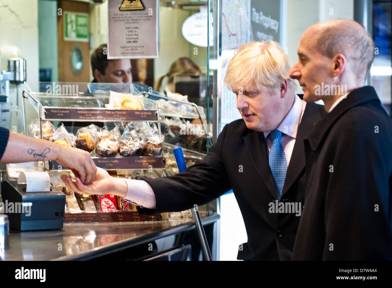 London, Regno Unito - 14 Maggio 2013: il sindaco di Londra Boris Johnson, paga per un caffè in un bar dopo che conduce un aborigeno di breve intorno a Wimbledon High Street per incontrare la popolazione locale come egli contribuisce a lanciare una consultazione pubblica sulla proposta di percorsi per Crossrail 2. Credito: Piero Cruciatti/Alamy Live News Foto Stock