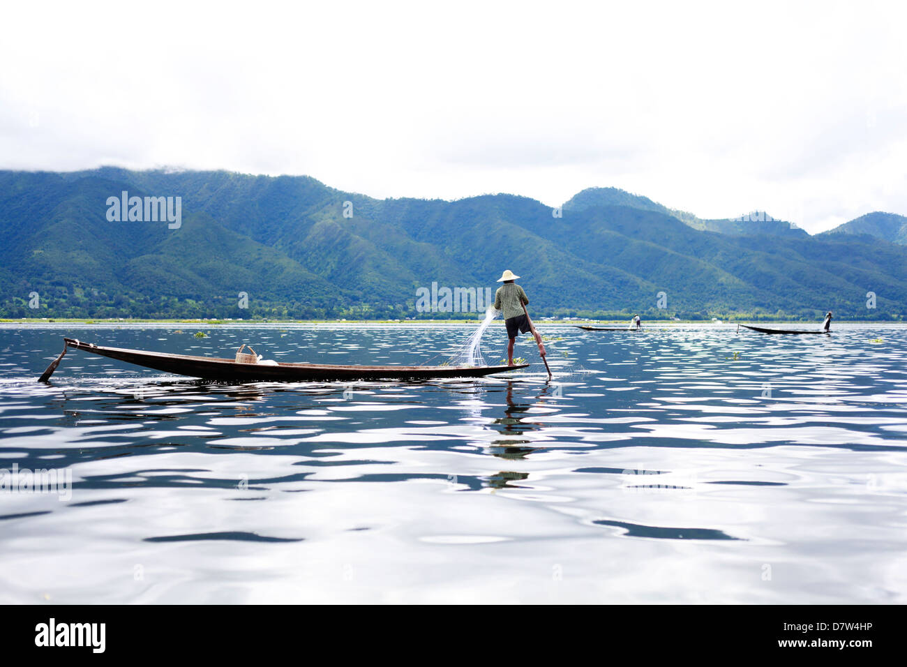 Un pescatore birmano utilizza il metodo tradizionale di remata la sua imbarcazione utilizzando la sua gamba, sul Lago Inle. Foto Stock