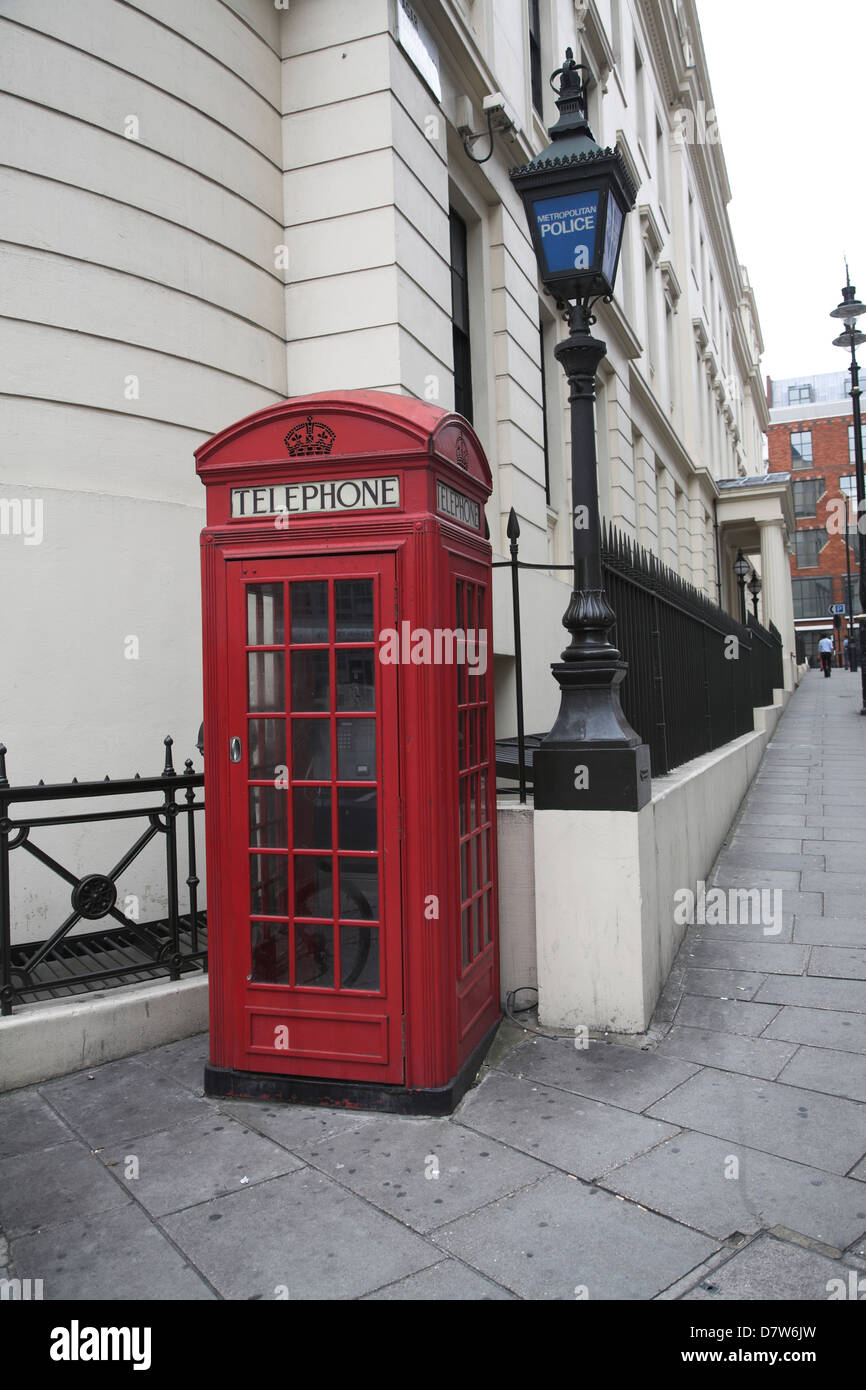 Telefono rosso box, Agar Street, al di fuori di carbonizzazione Cross stazione di polizia con la spia blu, Londra Foto Stock