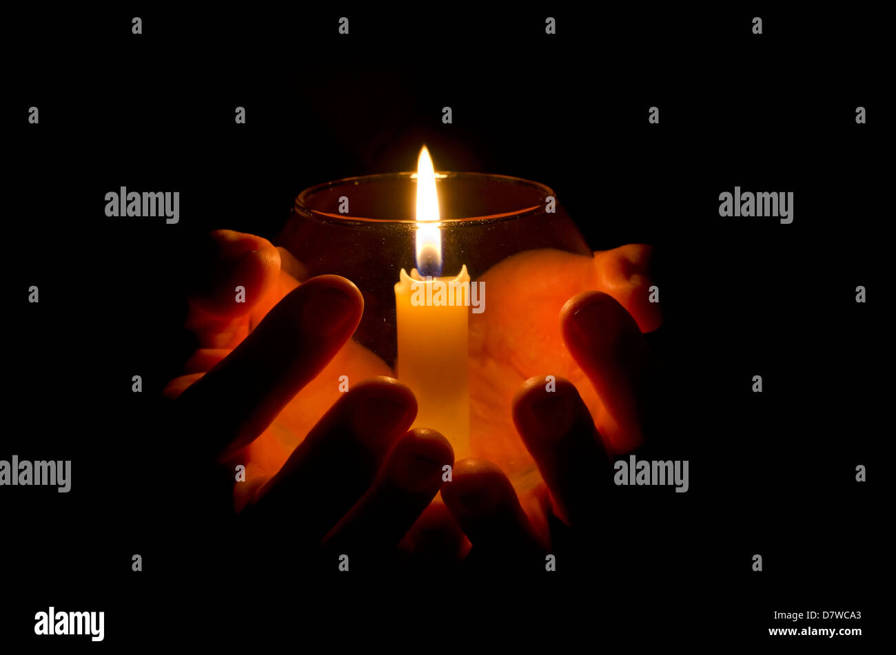 Una mano che tiene una candela accesa nel buio Foto Stock