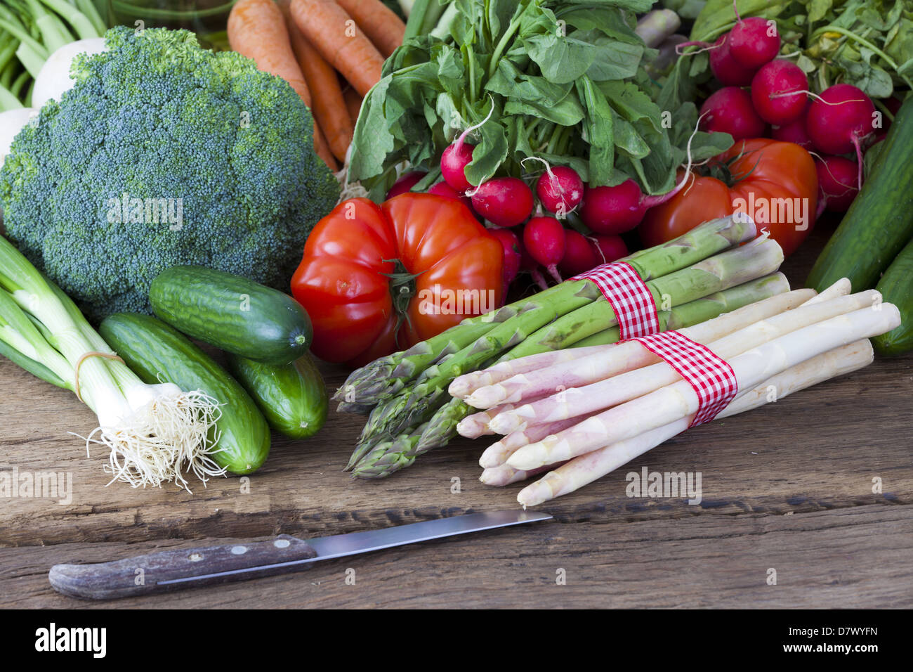 Fresco verde e asparagi bianchi è insieme ad altre verdure a molla e un coltello su un vecchio pannello di legno Foto Stock